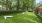a large green lawn with a bench and a brick building